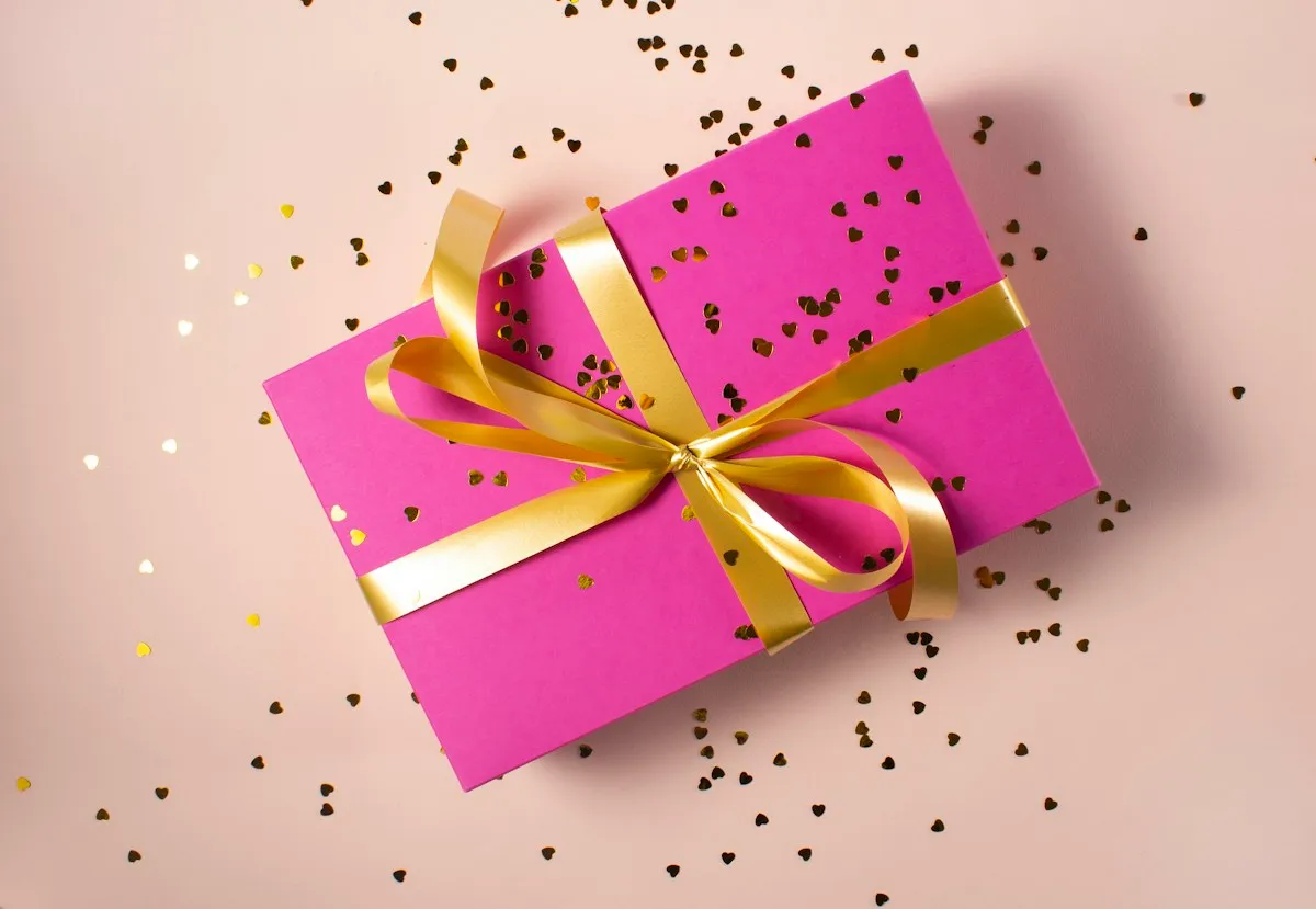 A pink gift box tied with a gold ribbon