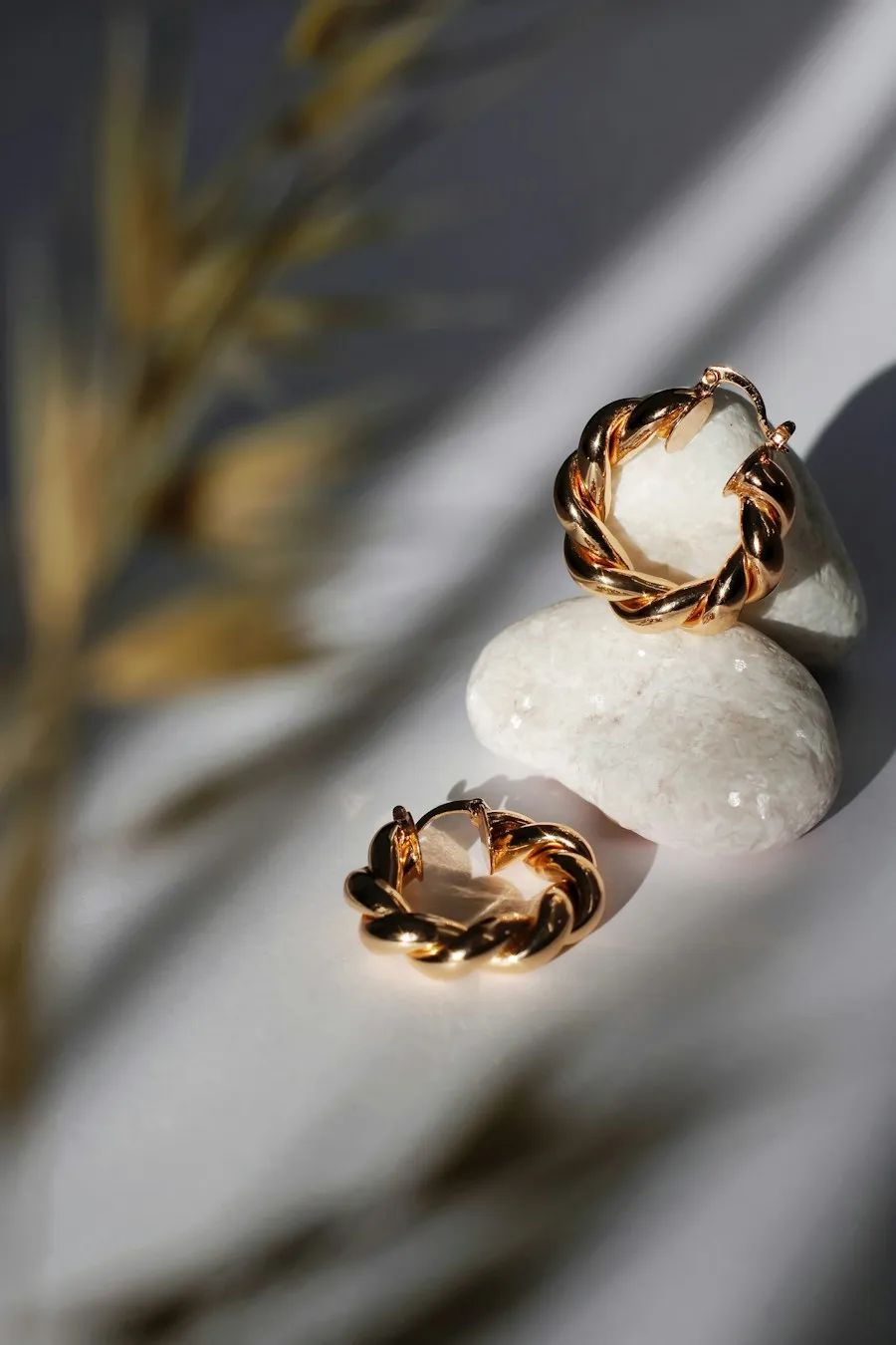 Gold earrings resting on a pale stone