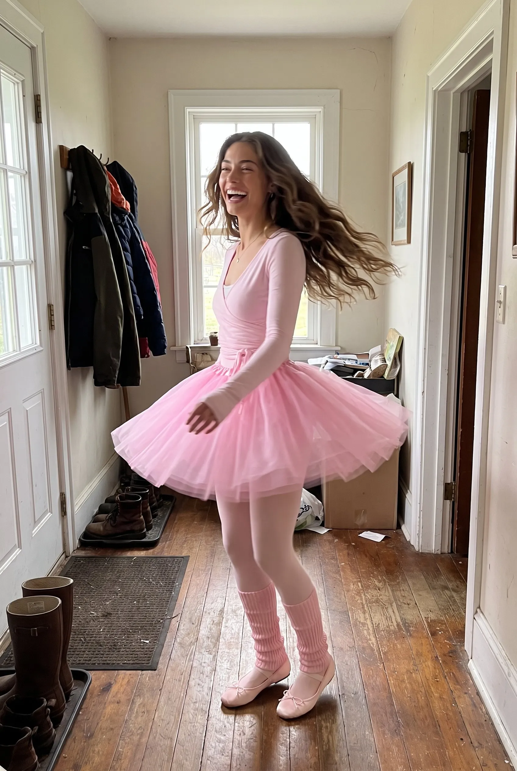 A brown haired woman twirling and laughing in her farmhouse hallway, wearing the pink tulle tutu, long sleeve wrap top, pink tights, leg warmers and satin ballet flats.